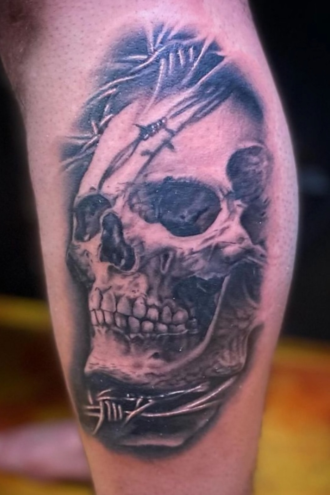 Black and grey skull with barbed wire tattoo by Byron Rojas